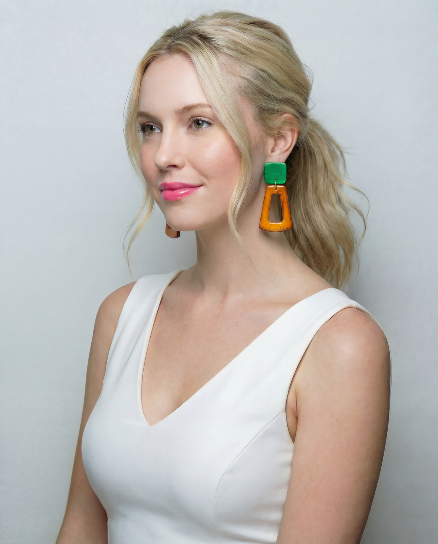 Woman wearing colorful earrings against a plain background