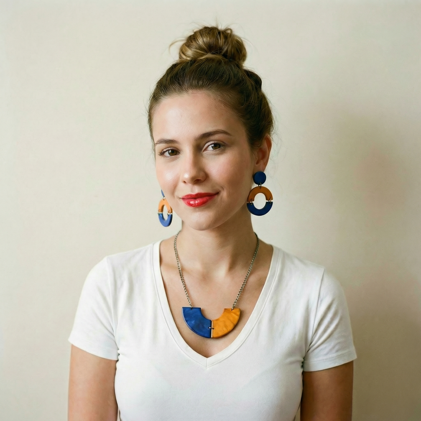 Woman wearing colorful earrings and a necklace against a plain background