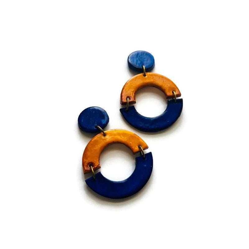 Pair of earrings with blue and mustard circular designs on a white background