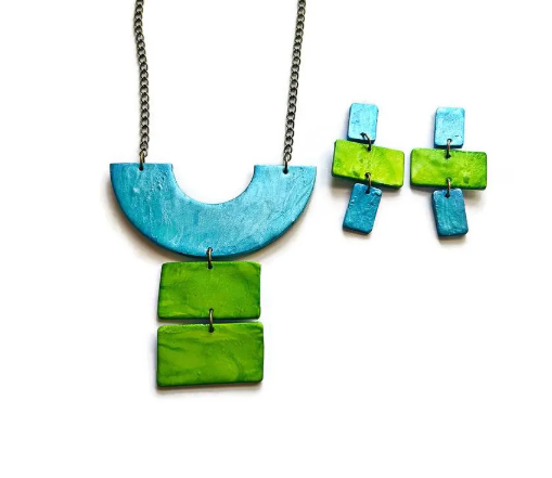 Necklace and earrings set with blue and green geometric shapes on a white background
