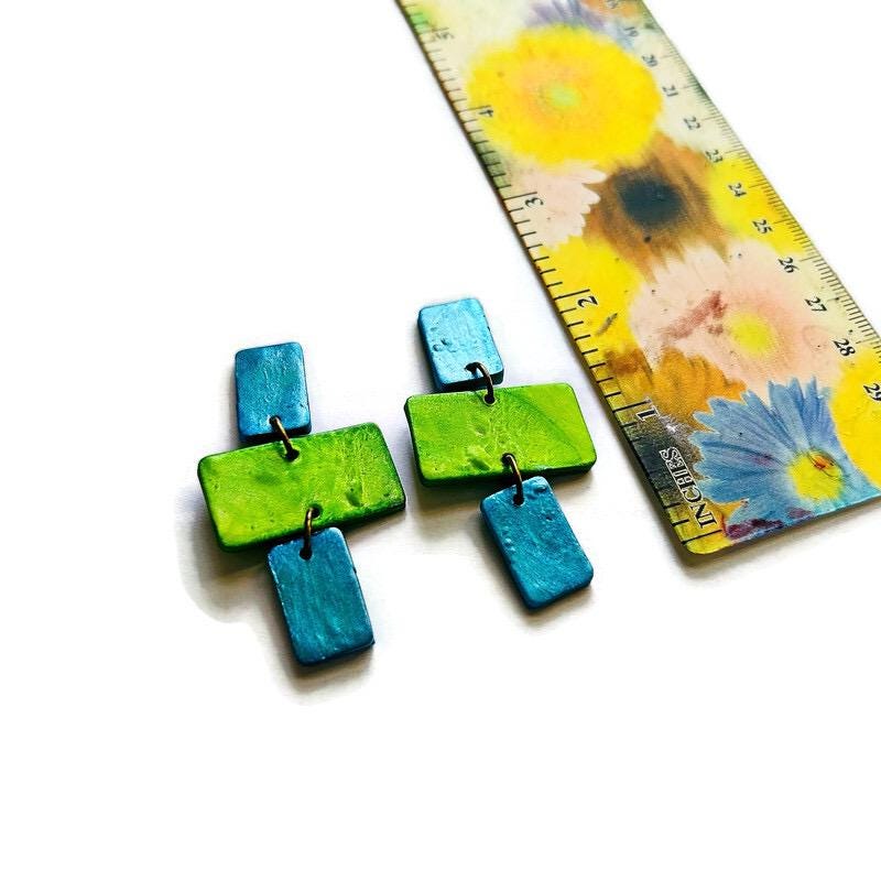 Colorful earrings with a ruler for scale on a floral background