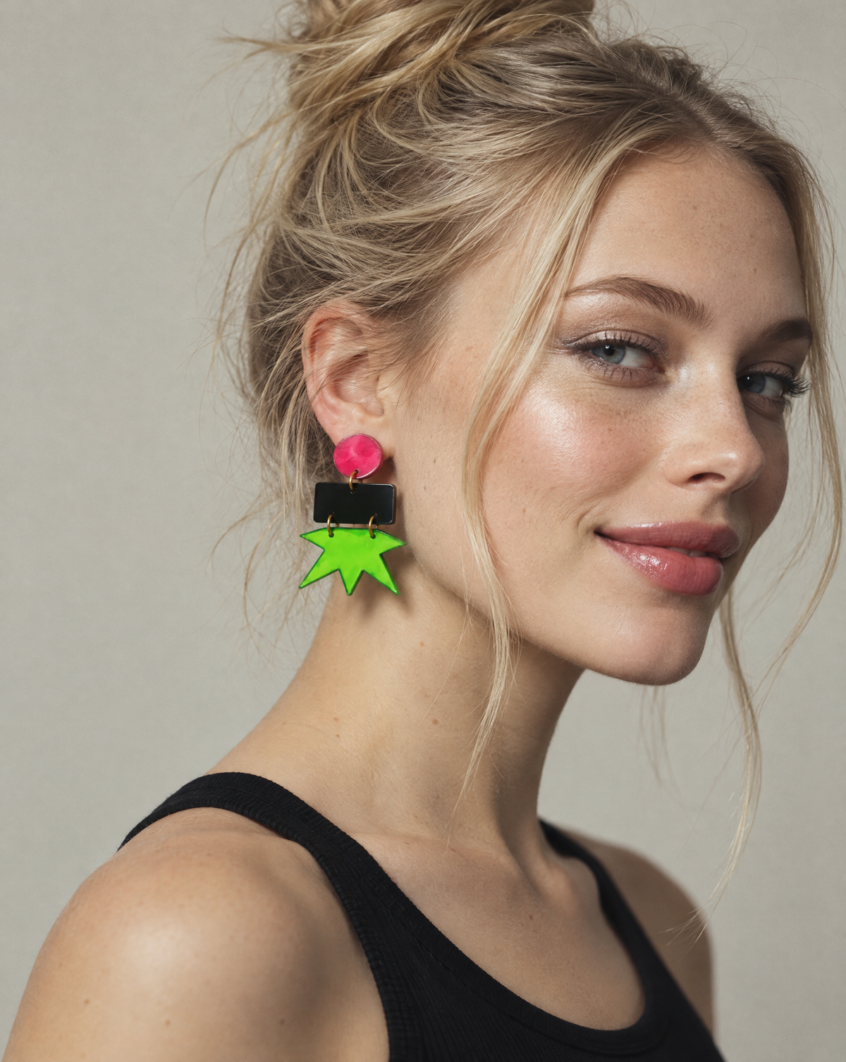 Geometric star earrings on model: pink round top, black block, neon green star charm