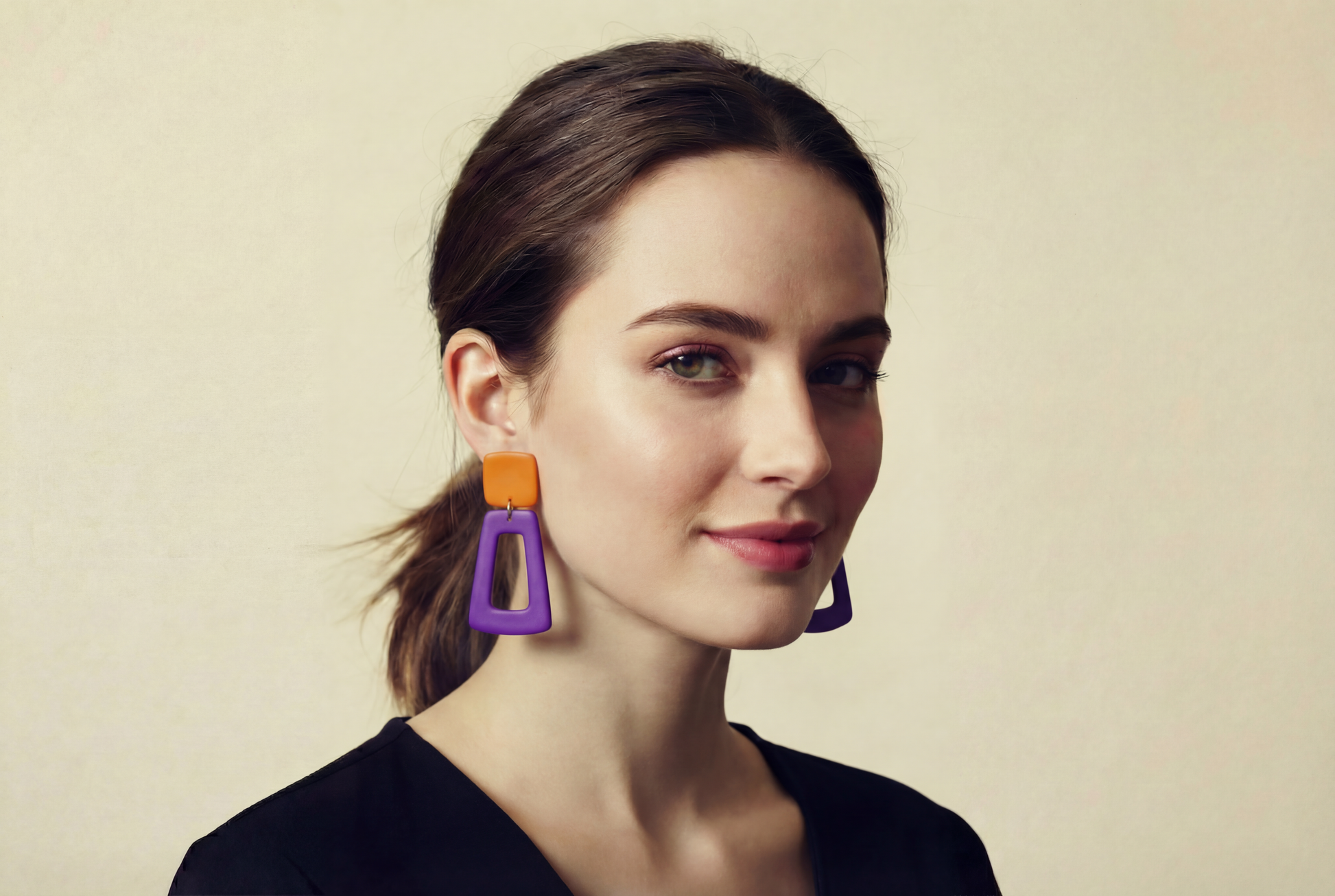 Woman wearing colorful earrings against a plain background