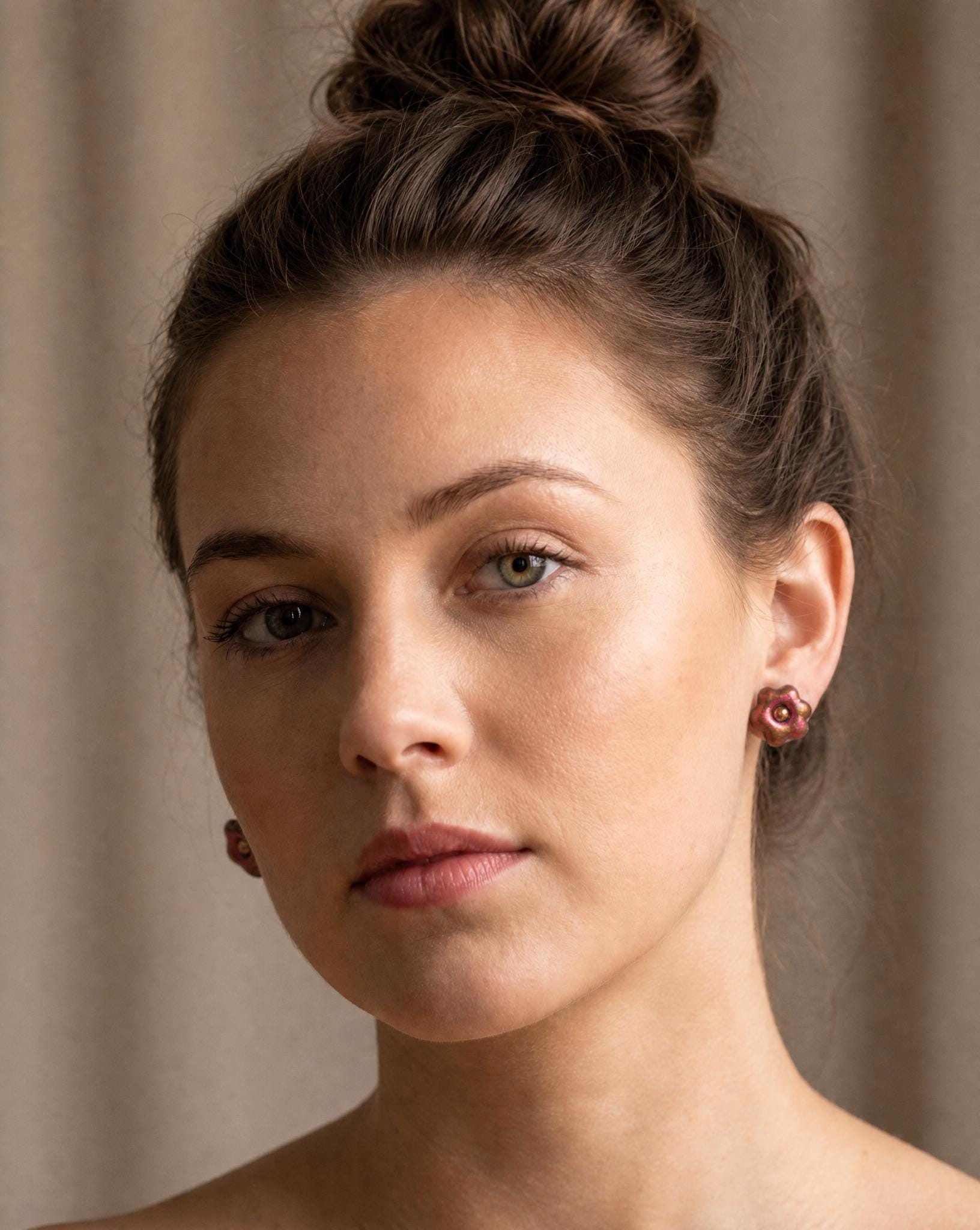 Copper pink floral stud earrings on model, small flower studs