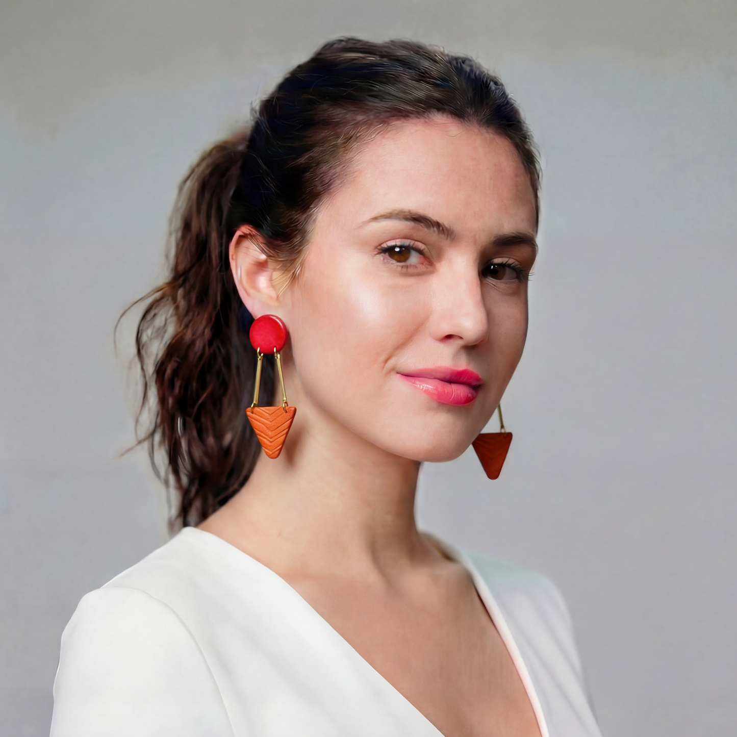 Woman wearing colorful earrings against a neutral background