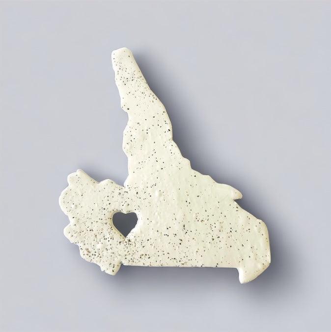 Off-white speckled PEI-shaped fridge magnet with heart cutout, side profile.