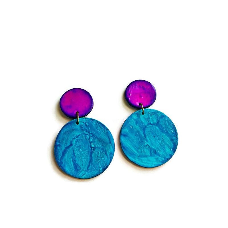 Pair of earrings with purple top and blue bottom on a white background