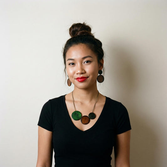 Woman wearing a black top with a necklace and earrings against a plain background