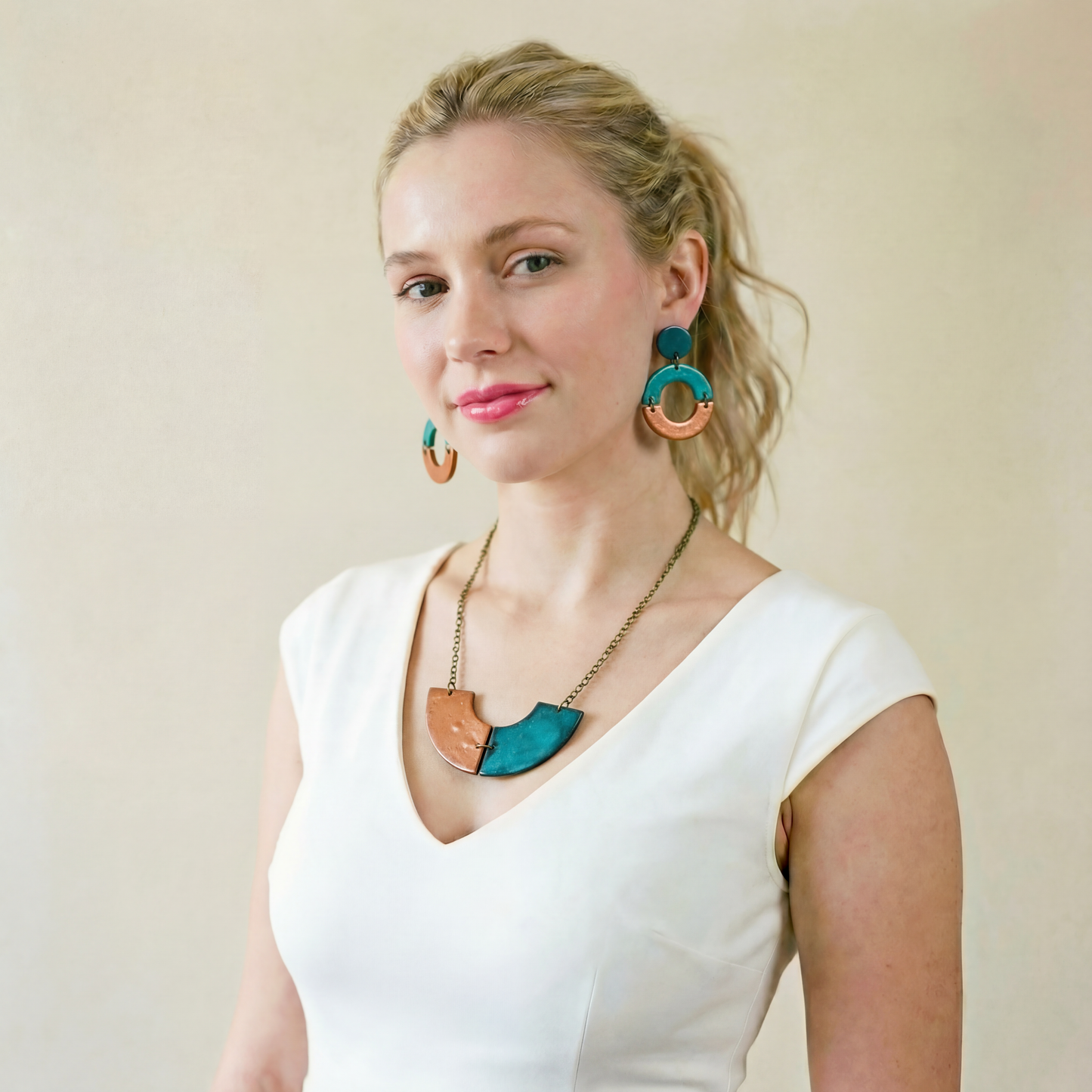 Woman wearing a white top and colorful jewelry against a plain background