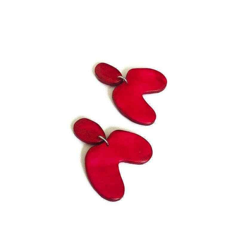Red asymmetric arch earrings with stud posts, two-piece clover shape on white